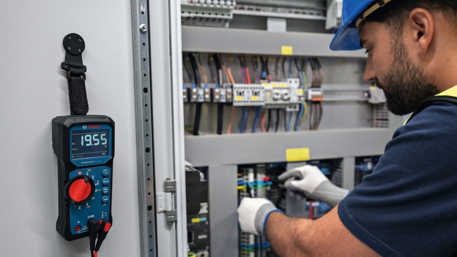 Elektryk mierzący pomiar elektryczności w szafie serwerowej.