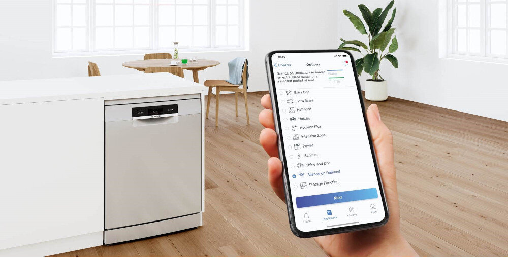 Polska produkcja i to na promocji?! Ta zmywarka Bosch już jest hitem sprzedaży Reka trzymająca smartfon z otwartą plikacją Home Connect na tle zmywarki Bosch SMV4ENX06E.