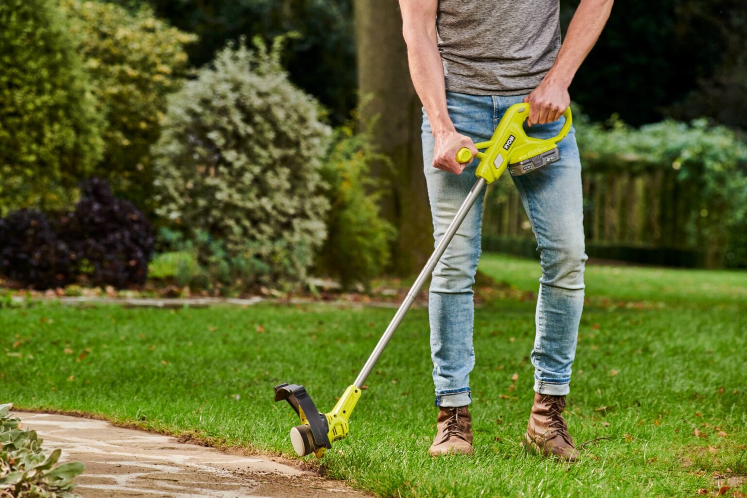 Podkaszarka akumulatorowa RYOBI RY18LT23A-0 podczas użytkowania na trawniku.